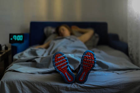 Woman in bed at 9:00 p.m. wearing tennis shoes after skipping exercise